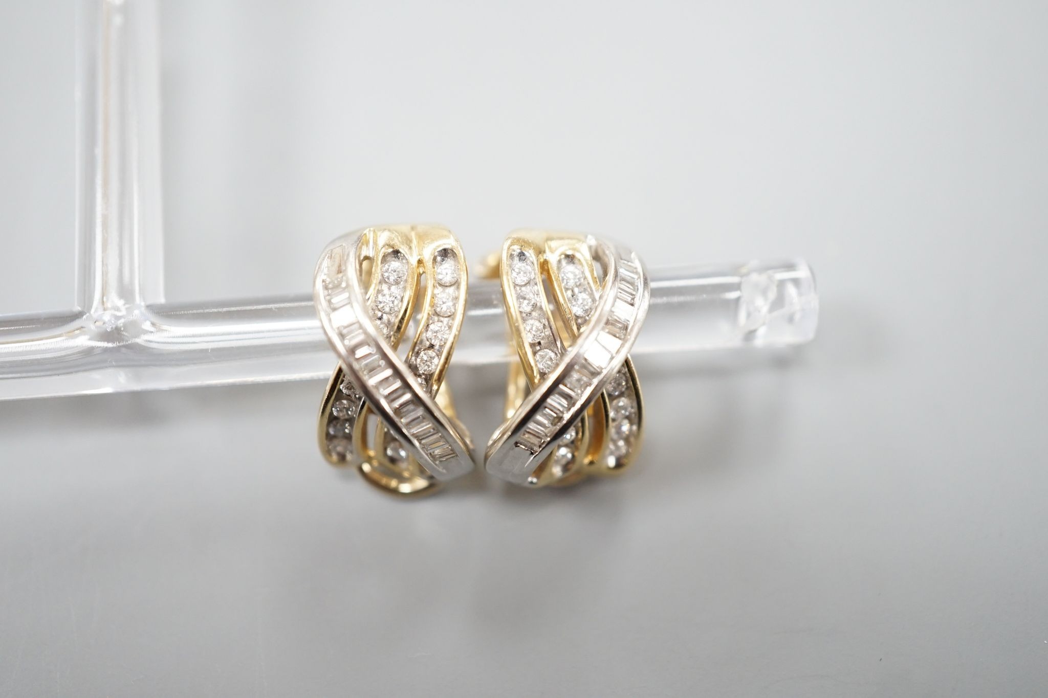 A modern pair of 14k, round and baguette cut diamond set triple row crossover earrings